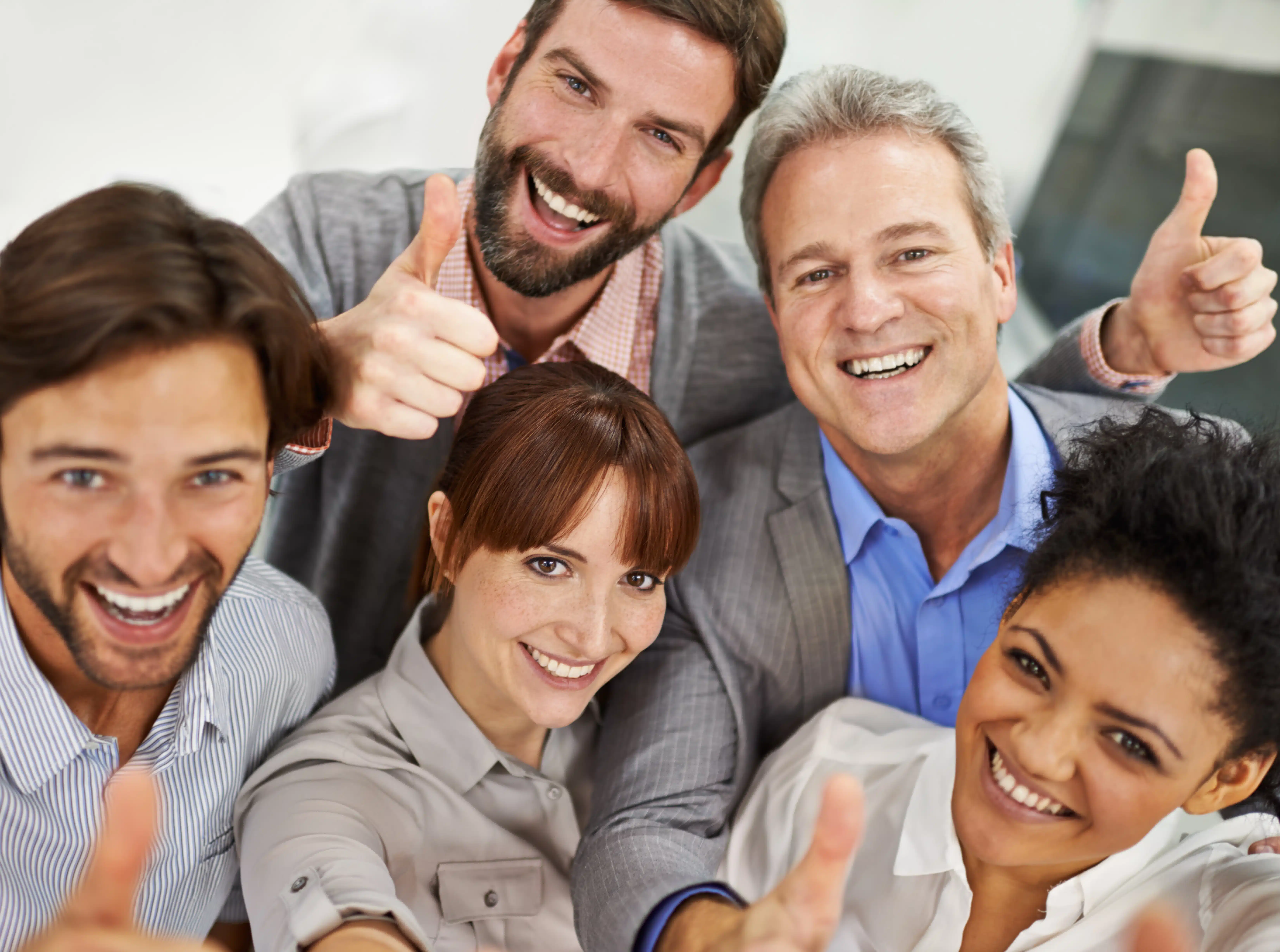 Portrait of a group of businesspeople giving the thumbs up to the camera.